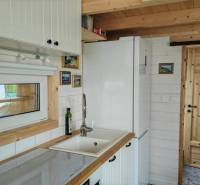 Kuchyně v rodinném domě s bílým nábytkem a dřevěnými prvky.