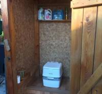 Dřevěná chata v Kráľovej nad Váhom s chemickým WC a poličkou.