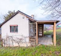 Chata v Prešově s dřevěnou konstrukcí a vinicí na travnatém kopci.