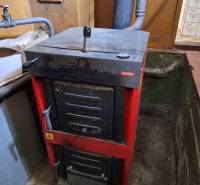Kotel na tuhá paliva ve sklepě rodinného domu, s připojenou rourou na odvod spalin.