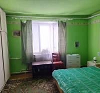 Zelený pokoj v rodinném domě s postelí, skříní a kobercem.