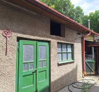 Rodinný dům v Tachtoch se dvěma zelenými dveřmi a světlou fasádou.