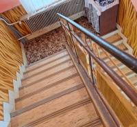 Schodiště s kobercem a podlahou s dřevěným dekorem v rodinném domě.