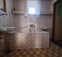 Koupelna v rodinném domě s kachličkami s květinovým vzorem a vanou.