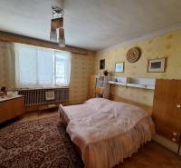 Ložnice v rodinném domě s retro nábytkem, koberec a žluté tapety.