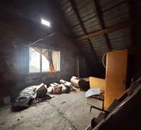 Podkrovní místnost s oknem v rodinném domě plná starých předmětů a nábytku.