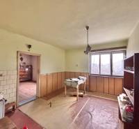 Interiér rodinného domu s nábytkem, oknem a podlahou s dřevěným dekorem.