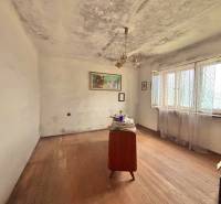 Pokoj v rodinném domě s jednoduchým nábytkem a podlahou s dřevěným dekorem.