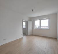 Světlý pokoj s podlahou s dřevěným dekorem v 2pokojovém bytě.