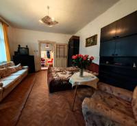 Obývací pokoj v rodinném domě s pohovkami, TV a podlahou s dřevěným dekorem.