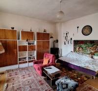 Obývací pokoj v rodinném domě s kobercem, pohovkou a policovým úložným systémem.