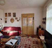 Obývací pokoj v rodinném domě se starožitným nábytkem a dekoracemi, podlaha s dřevěným dekorem.