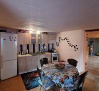 Kuchyně v rodinném domě s jídelním stolem, kuchyňskou linkou a lednicí.