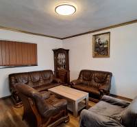 Obývací pokoj v rodinném domě s koženými sedacími soupravami a podlahou s dřevěným dekorem.