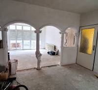 Interiér rodinného domu s klenutými oblouky a prosklenými dveřmi. Probíhají opravy.