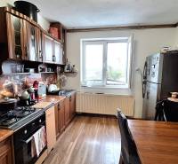 Kuchyně rodinného domu s kuchyňskou linkou, spotřebiči a podlahou s dřevěným dekorem.