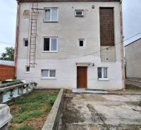 Rodinný dům v Zacharovcích s jednoduchou fasádou, okny a venkovním schodištěm.