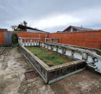 Dvůr rodinného domu v Zacharovcích s květinovým záhonem a betonovým chodníkem.