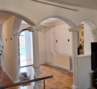 Interiér rodinného domu s obloukovými sloupy a podlahou s dřevěným dekorem.