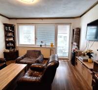 Obývací pokoj v rodinném domě s koženým nábytkem a podlahou s dřevěným dekorem.