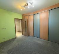 Pokoj v 3-pokojovém bytě s barevnou stěnou, skříní a světlým osvětlením.