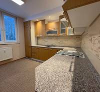 Kuchyně v 3-pokojovém bytě s podlahou s dřevěným dekorem a moderní linkou.