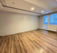 Obývací pokoj v 3-pokojovém bytě s podlahou s dřevěným dekorem a velkým oknem.