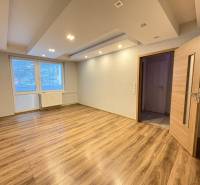 Pokoj v 3-pokojovém bytě s podlahou s dřevěným dekorem a velkým oknem.