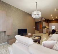 Obývací pokoj v 3-pokojovém bytě s béžovou pohovkou a vzorovanou tapetou.