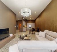 Obývací pokoj v 3pokojovém bytě s pohodlnou sedačkou, lustrem a televizí.