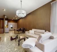 Obývací pokoj s béžovou sedačkou a otevřenou kuchyní v 3-pokojovém bytě.