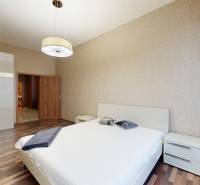 Ložnice v 3-pokojovém bytě s postelí, skříní a podlahou s dřevěným dekorem.