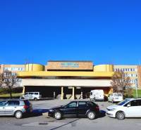 Budova nemocnice na Antolské ulici v Petržalce, Bratislava, s parkovištěm a auty.