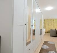 Chodba s bílou zrcadlovou skříní a podlahou s dřevěným dekorem v 2-pokojovém bytě.