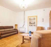 Obývací pokoj v rodinném domě s podlahou s dřevěným dekorem, pohovkou a křesly.