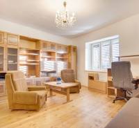 Interiér rodinného domu s nábytkem, podlahou s dřevěným dekorem a lustrem.