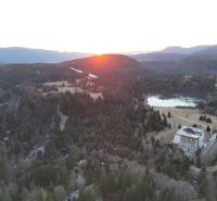 Západ slunce v Krpáčově nad lesy, jezerem a budovami na ulici Krpáčovo.