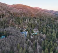 Letecký pohled na chaty v lese v oblasti Krpáčovo obklopené horami a hustými stromy.