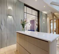 Interiér 4-pokojového bytu s designovou stěnou, světlým nábytkem a květinami na stole.