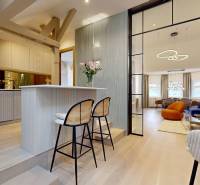 Interiér 4-pokojového bytu se skleněnou příčkou, barovým pultem a podlahou s dřevěným dekorem.