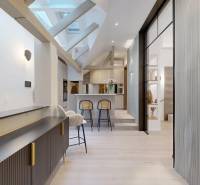 Interiér 4-pokojového bytu s podlahou s dřevěným dekorem, stropními trámy a kuchyňským pultem.