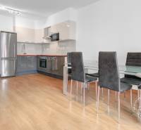 Kuchyně v 3-pokojovém bytě s podlahou s dřevěným dekorem, sklokeramický stůl a židle.