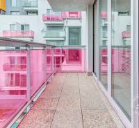 Balkon s růžovým zábradlím a prosklenými dveřmi ve 3-pokojovém bytě.