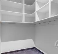 Šatník ve 3-pokojovém bytě s bílými poličkami a keramickou podlahou.