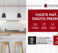 Kuchyně se světlou pracovní deskou, ostrůvkem, dvěma dřevěnými židlemi a závěsnými lampami.