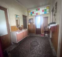 Chodba v rodinném domě má koberec a barevná skleněná okénka nad dveřmi.