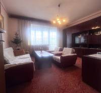 Obývací pokoj v rodinném domě s červeným kobercem a sedací soupravou.