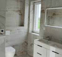 Koupelna s moderním umyvadlem, zrcadlem s osvětlením a obklady ve 3-pokojovém bytě.