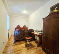 Ložnice s starožitným nábytkem, postelí a skříní s podlahou s dřevěným dekorem.