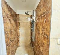 Sprchový kout s keramickým obkladem a závěsem ve 3-pokojovém bytě.